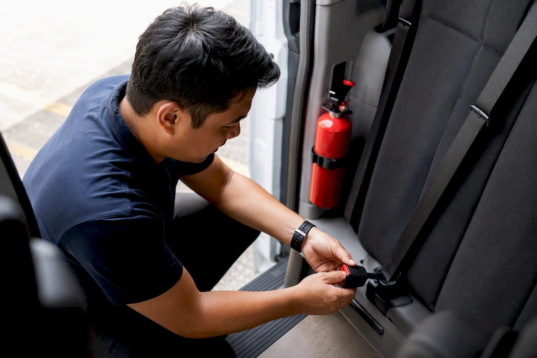 Organizer checking seatbelts during van handoff