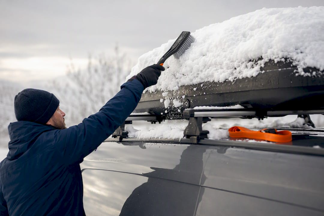 Snow being cleared from a roof cargo box