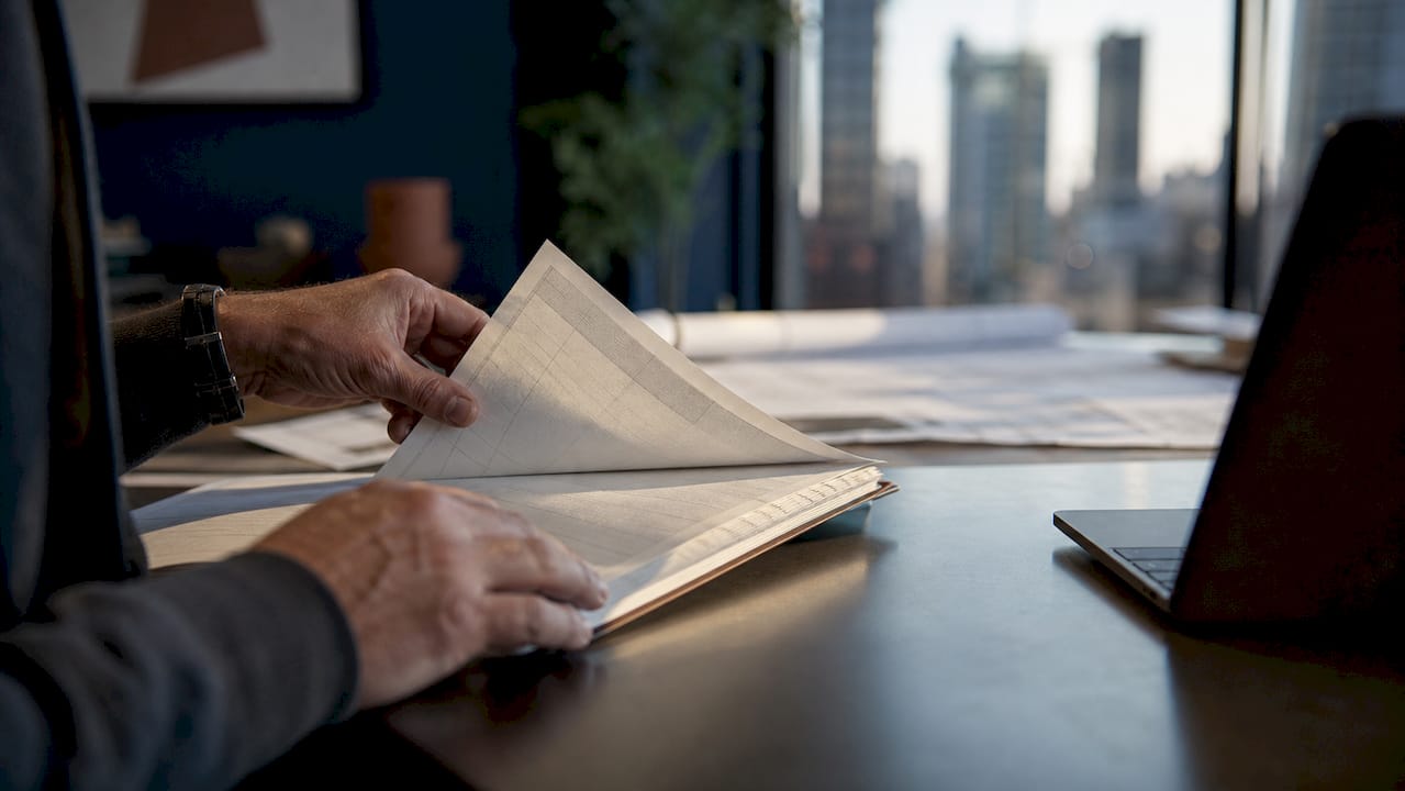 Hands reviewing construction cost ledger