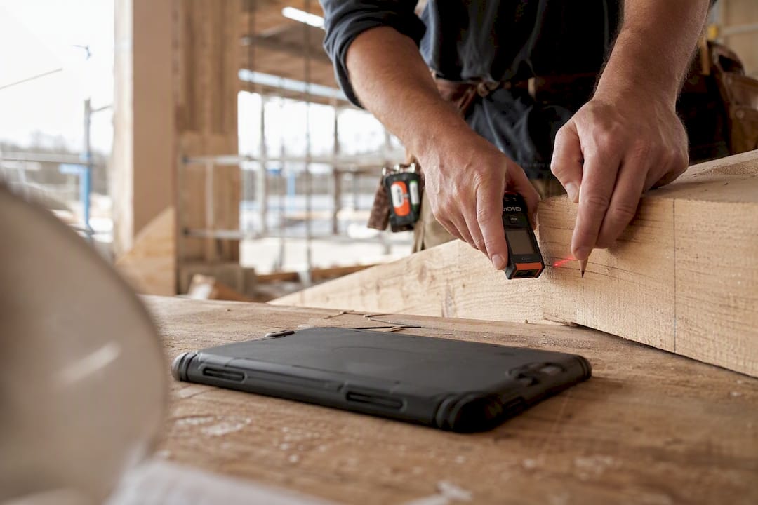Hands measuring steel beam on construction site workbench