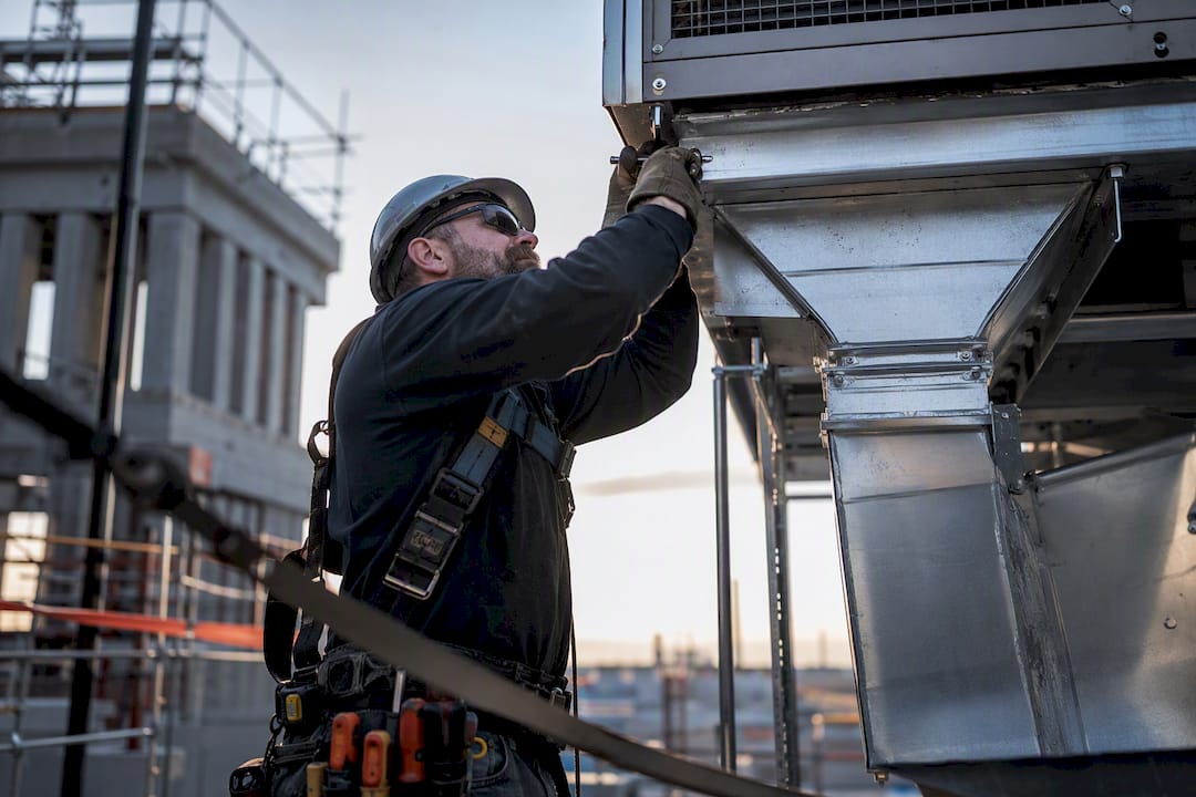HVAC crew worker attaching rooftop unit duct