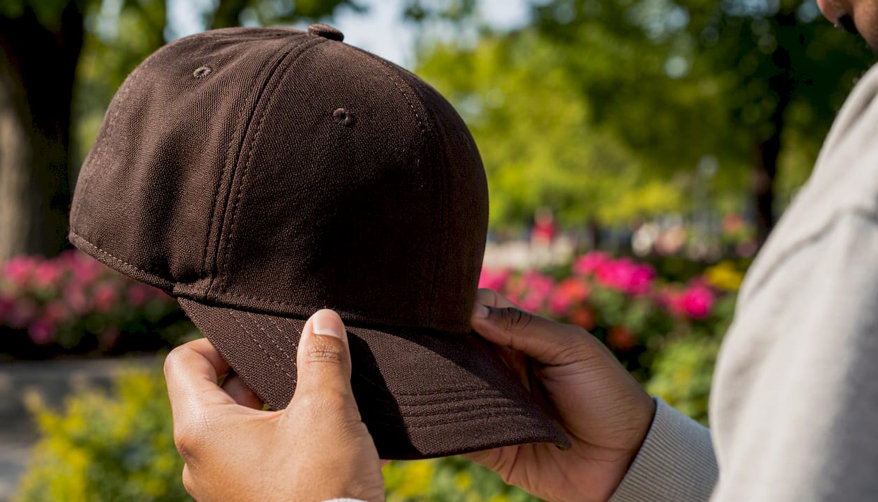 Person adjusting baseball cap brim outdoors