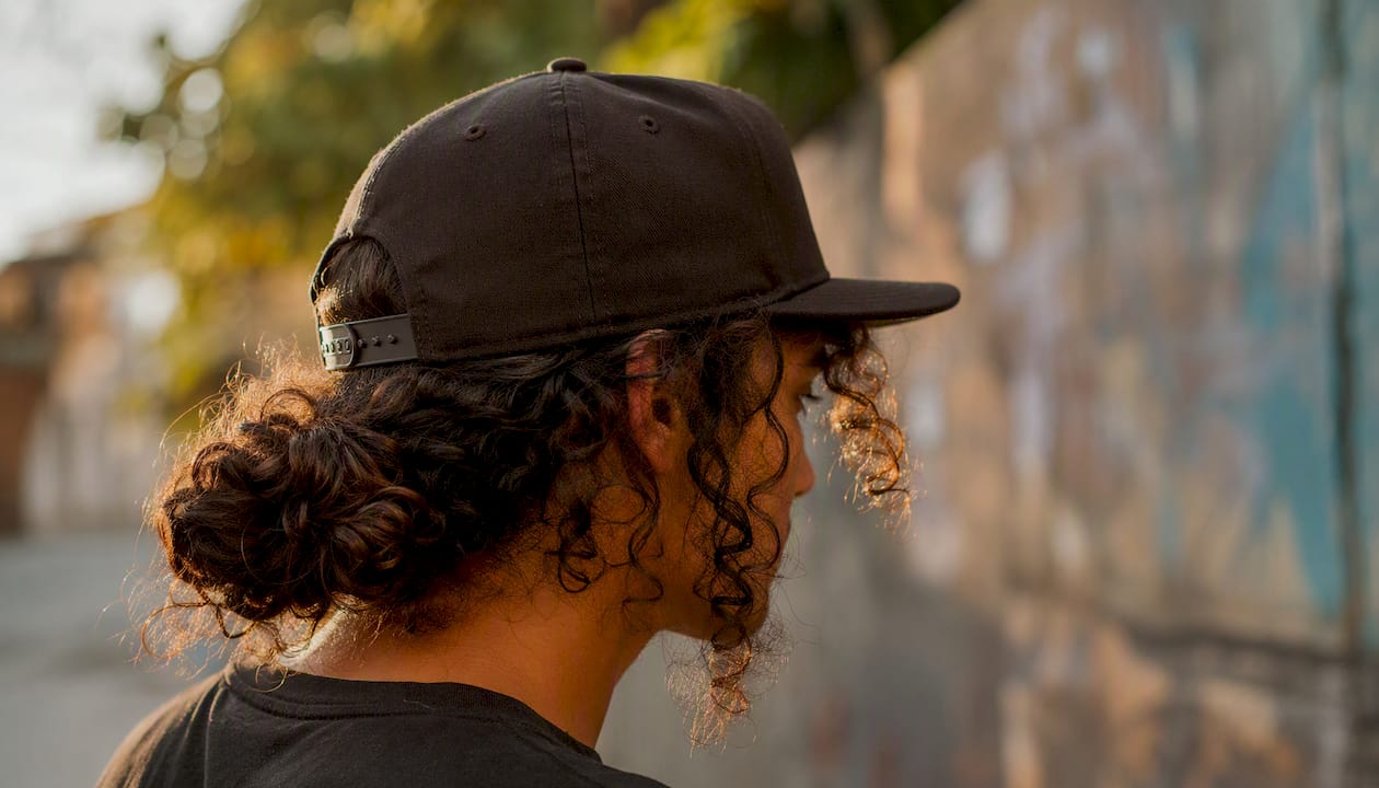 Curly hair tied low bun under snapback cap
