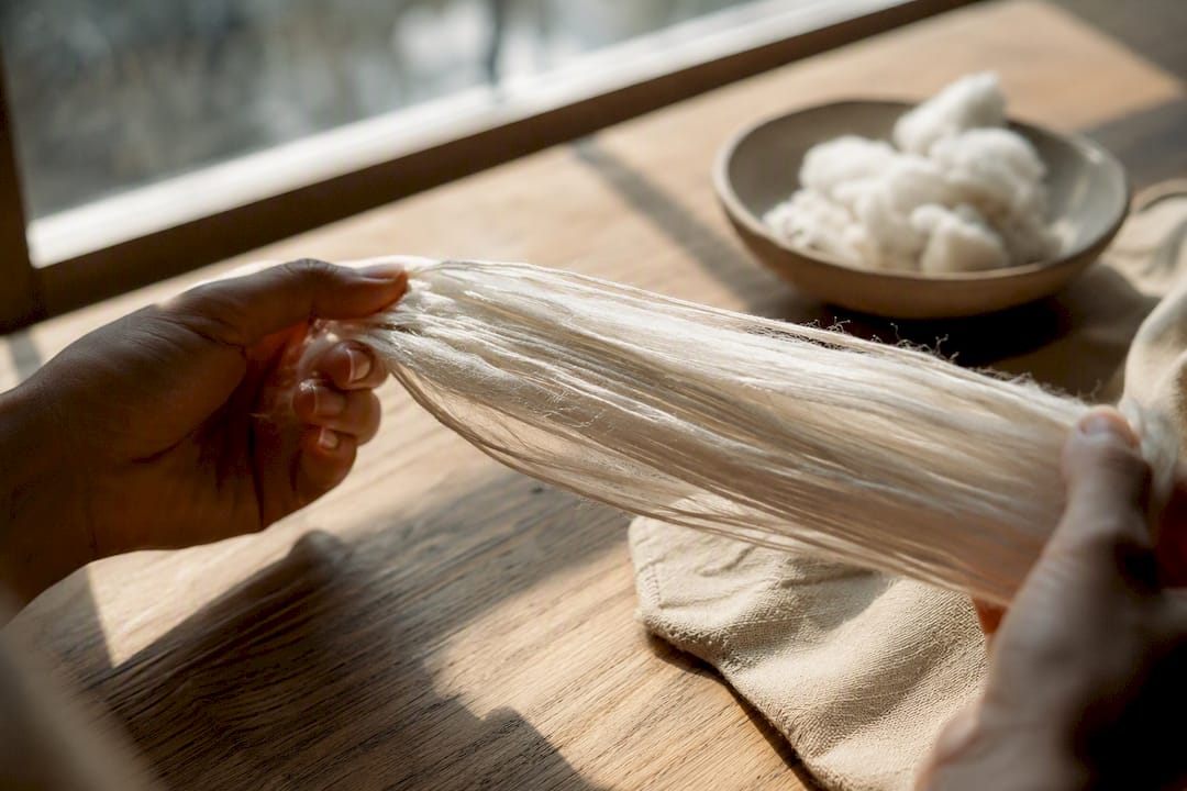 Hands stretching long staple cotton fibers