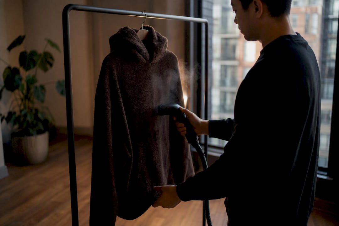 Person steaming fleece hoodie to freshen it