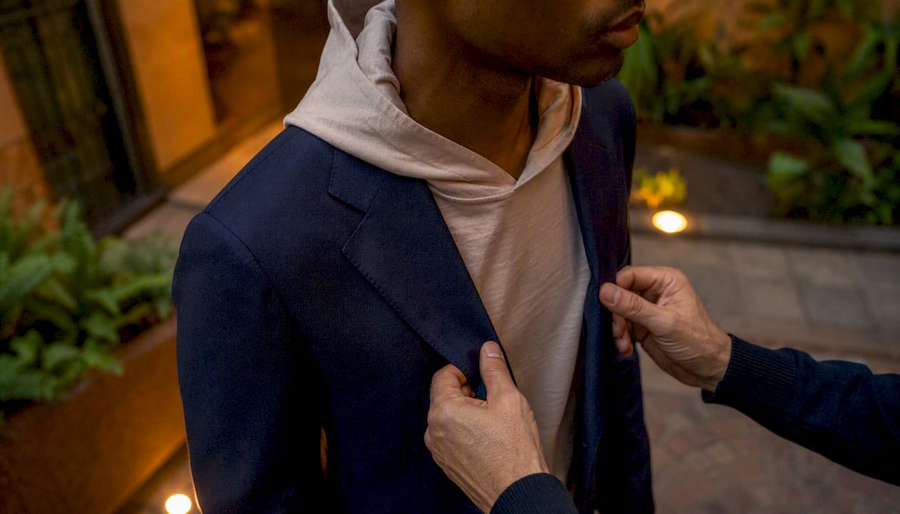Hands adjusting blazer lapel over hoodie