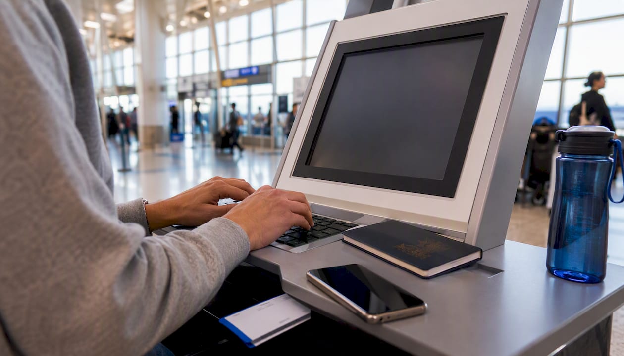 Traveler entering passport info at airport self-check-in kiosk