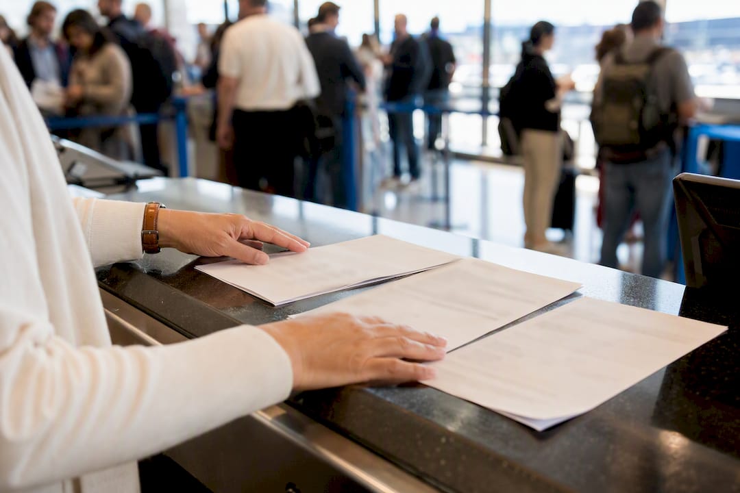 Hands arranging travel documents at airport counter