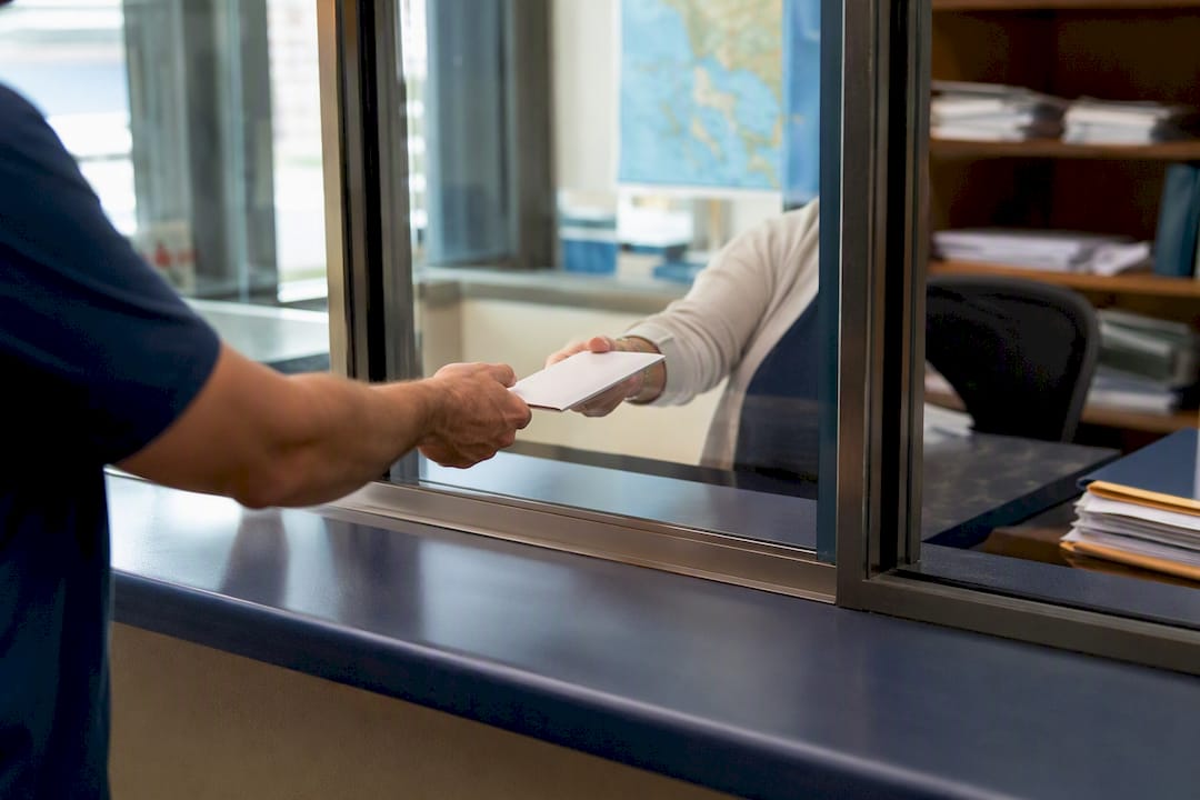 Courier handing passport envelope to agency receptionist