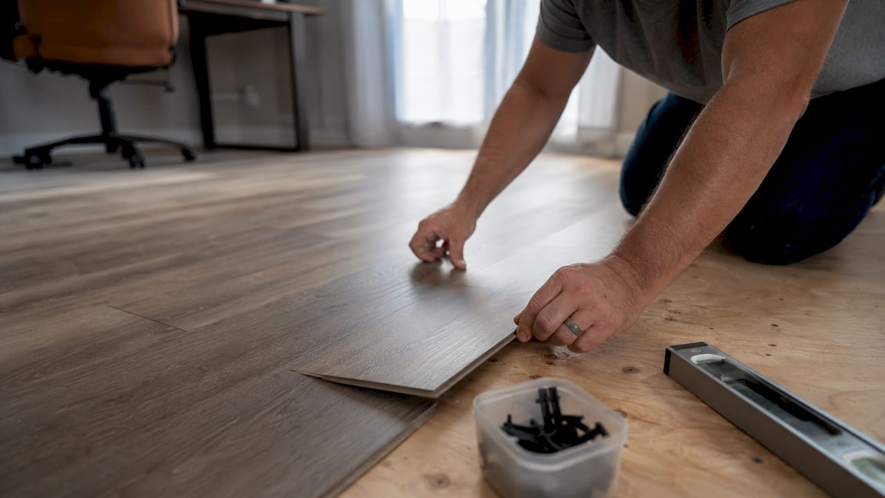Installer hands positioning luxury vinyl plank flooring