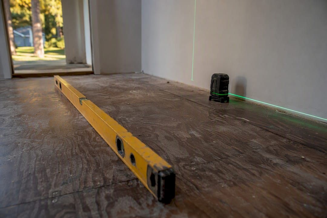Chalk line and laser level on hardwood subfloor