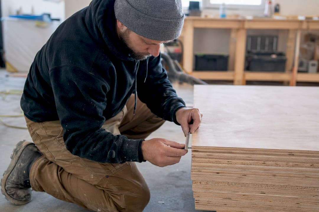 Installer measuring fastener length against plywood overlay