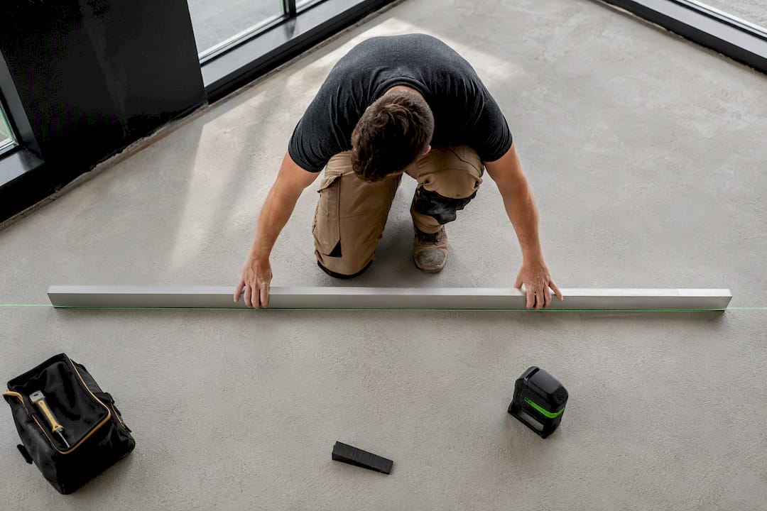 Installer checking concrete slab with straightedge