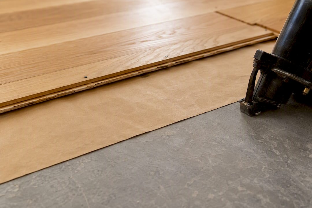 Slip sheet beneath partial wood floor assembly