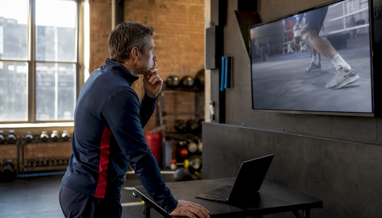 Coach reviewing athlete footwork video analysis indoors
