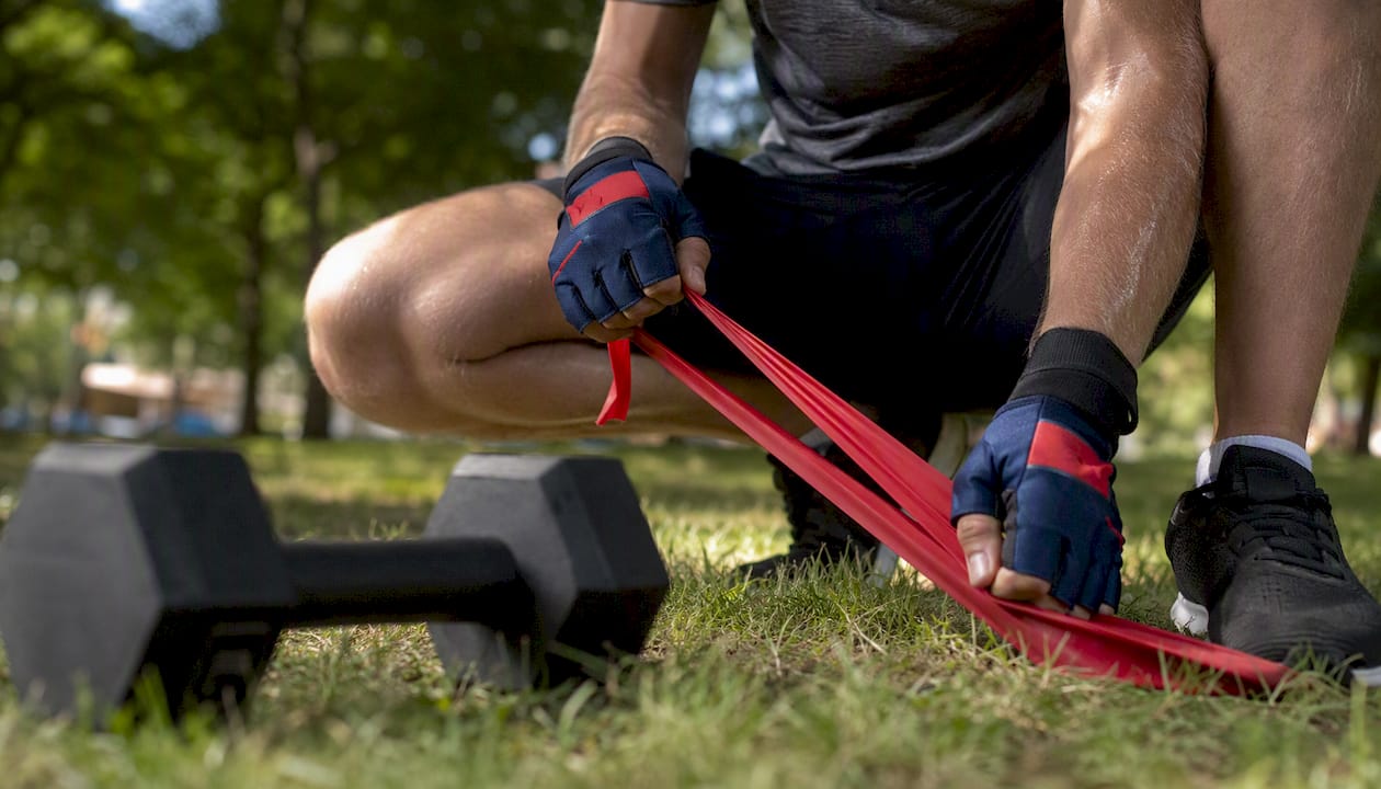 Athlete hands stretching resistance band with dumbbells nearby