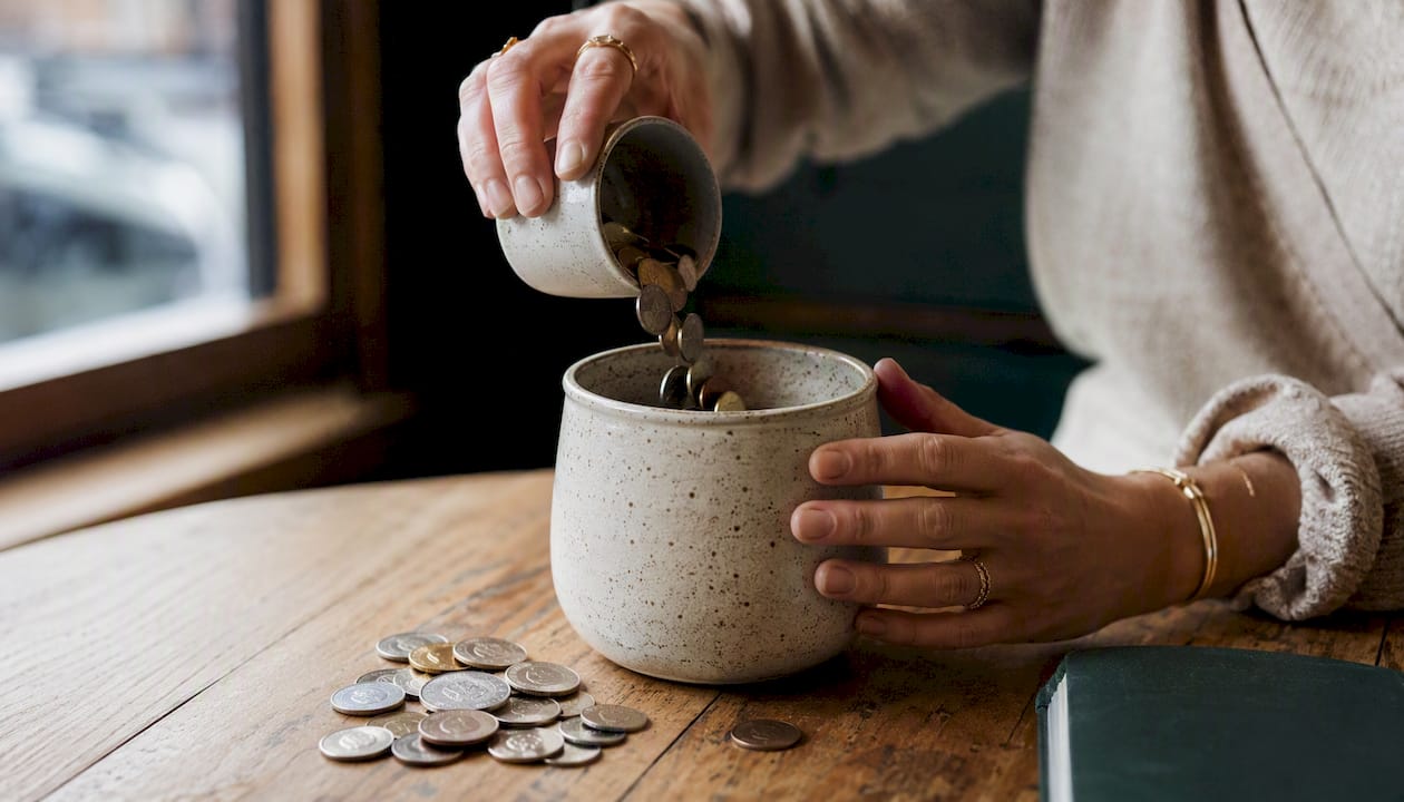 Hands pouring coins into cash reserve jar