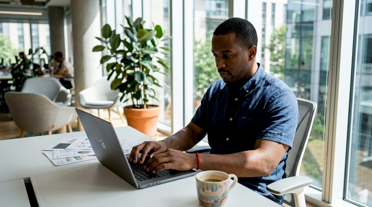 Hands typing beside Microsoft plan feature sheet