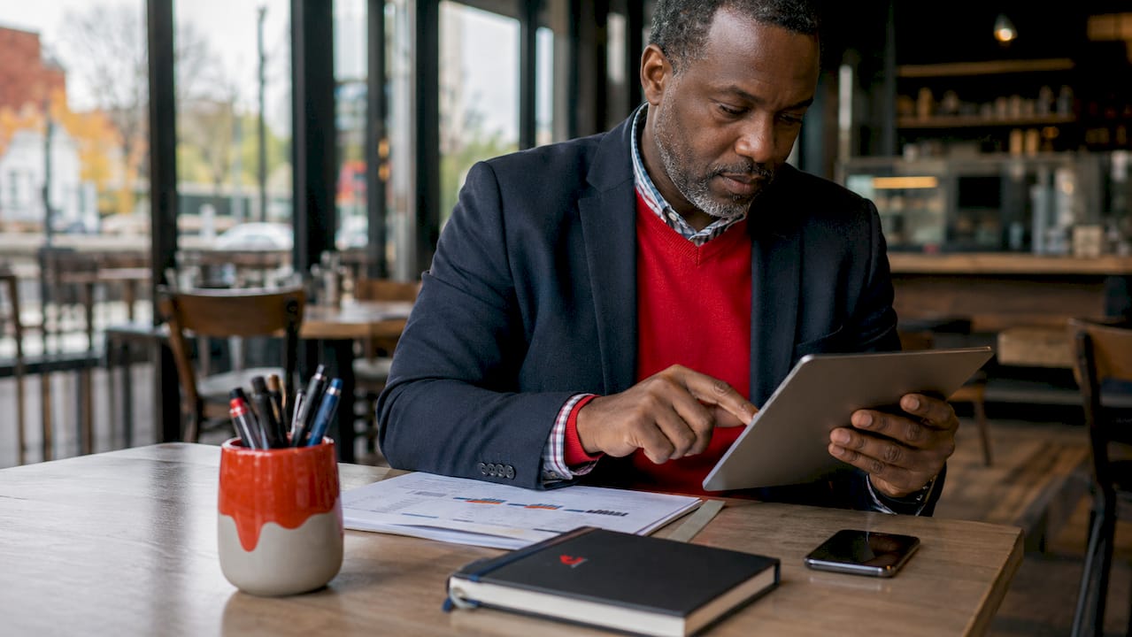 Hands scrolling tablet with reports on desk
