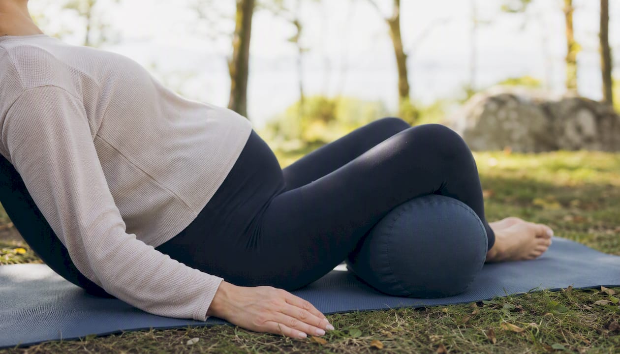 Person performing supported restorative yoga with bolster