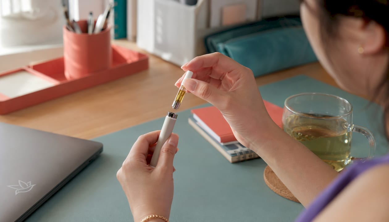 Hands inserting vape cartridge into adjustable battery sleeve