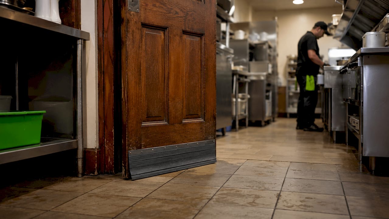 Door sweep sealing restaurant exterior door gap