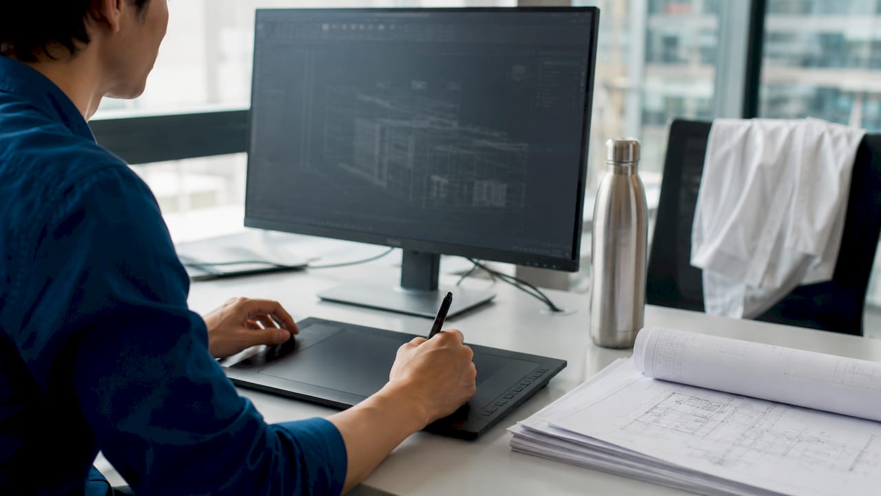 Hands interacting with AutoCAD Architecture tools at desk