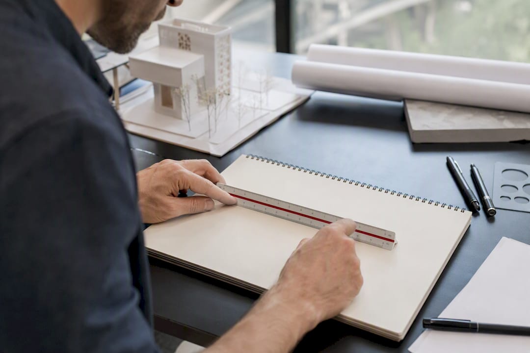 Hands holding scale ruler over drafting mat