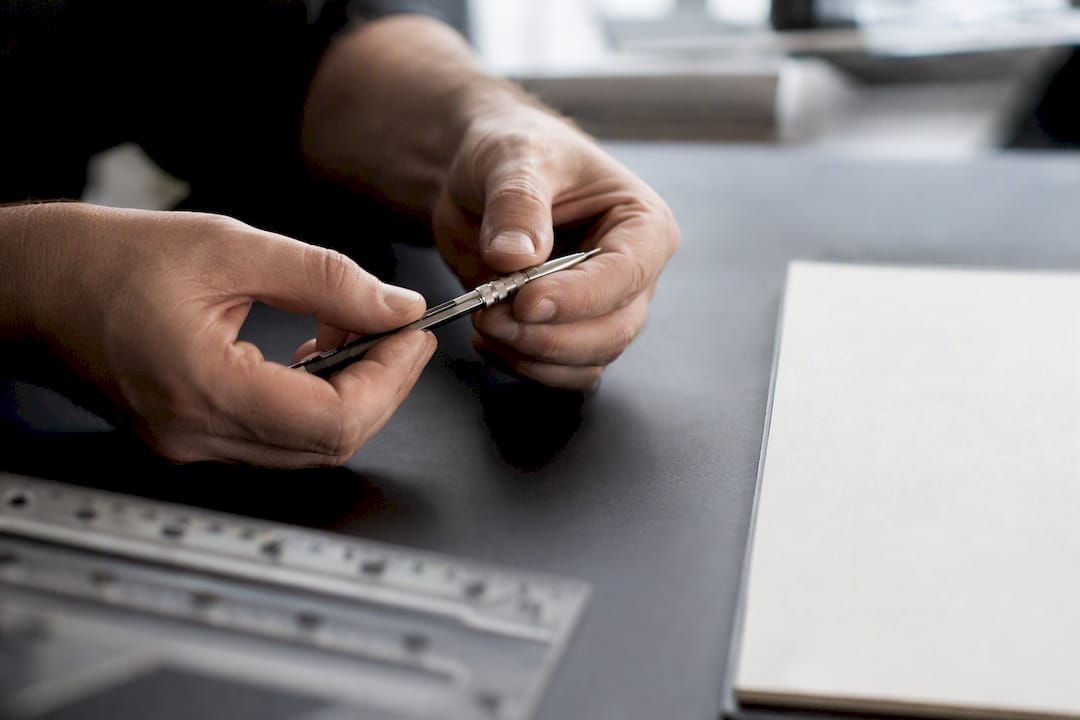 Hands adjusting drafting compass on desk