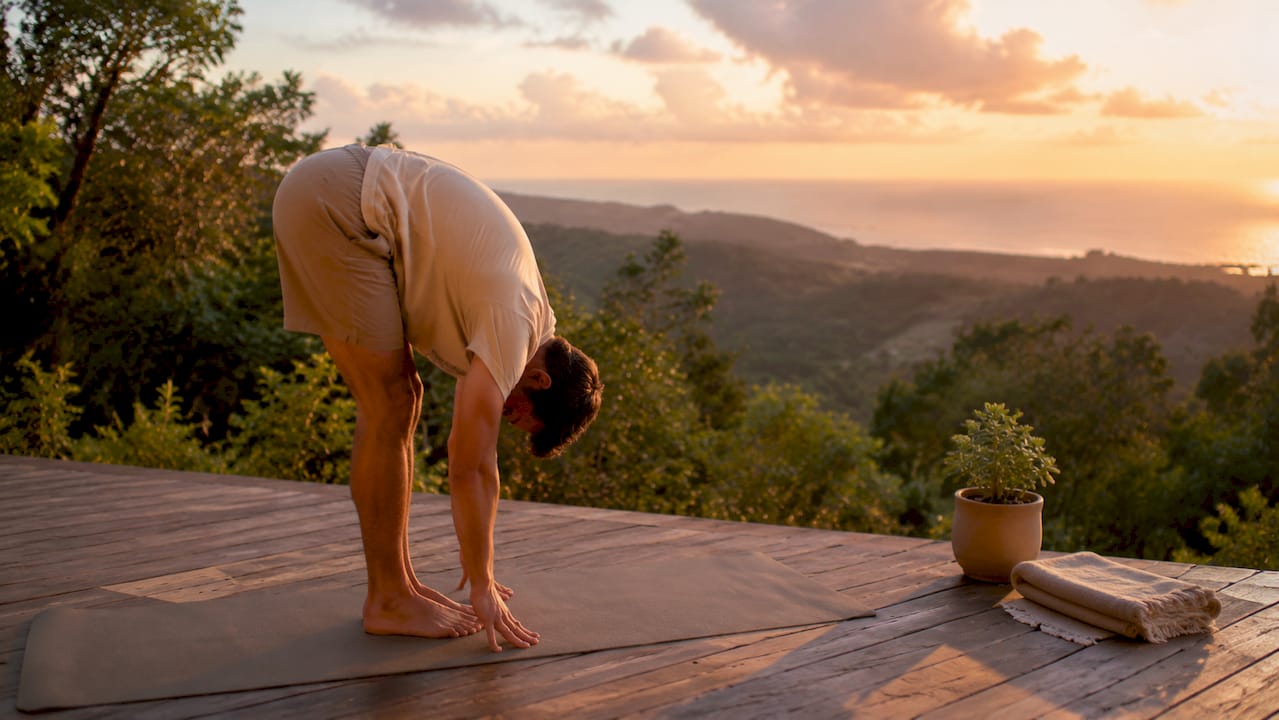 Man doing yoga stretch in backyard in soft sunlight