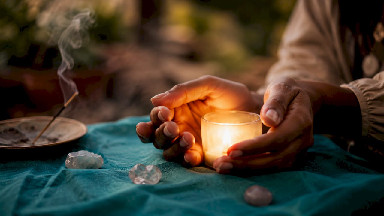 Close-up hands holding glowing crystal at altar