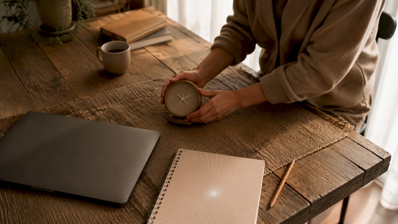 Hands adjusting timer on office desk at sunrise