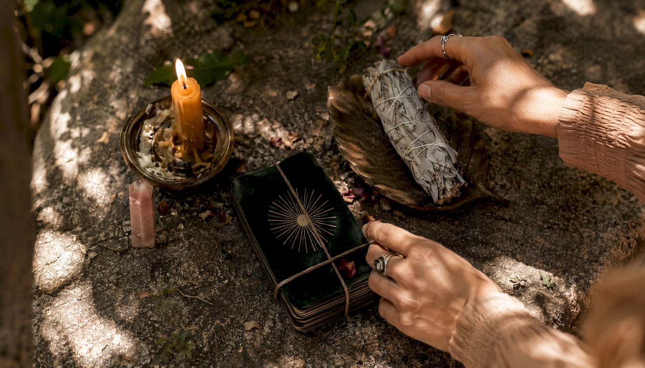 Hands arranging candle and tarot deck on ritual altar