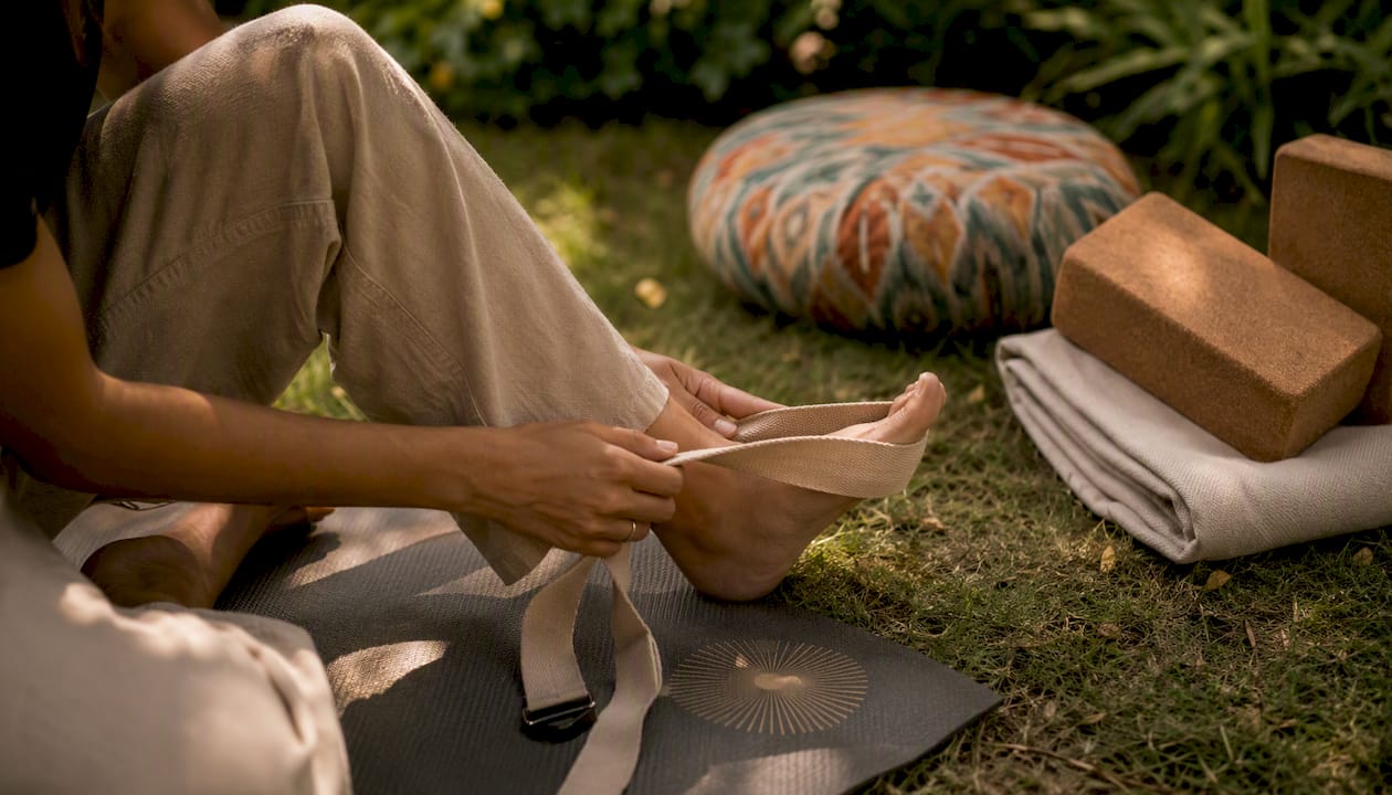 Hands adjusting yoga strap with mats and props