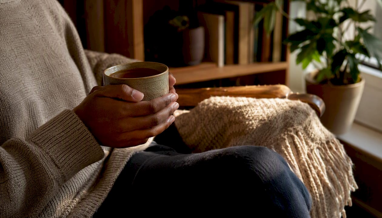 Hands holding mug in calm living room corner