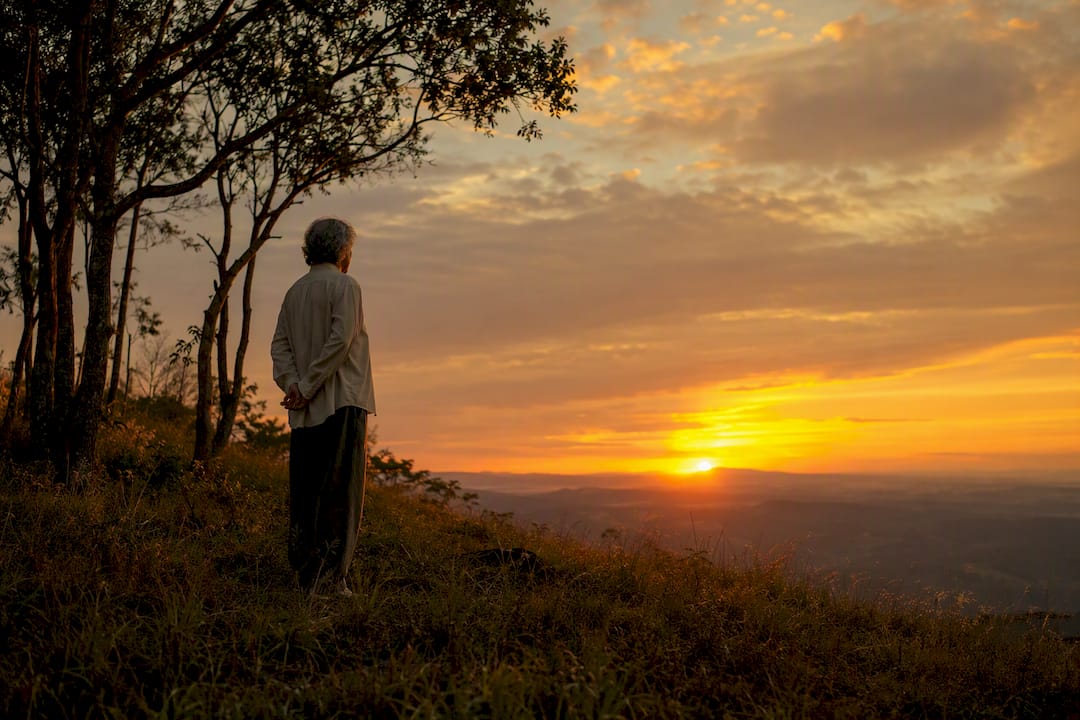Adulto de mediana edad sentado en un banco al atardecer.
