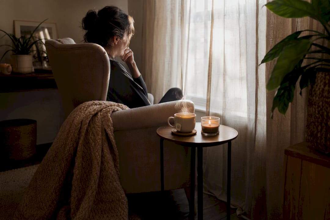 Unmade bed and candlelit water glass