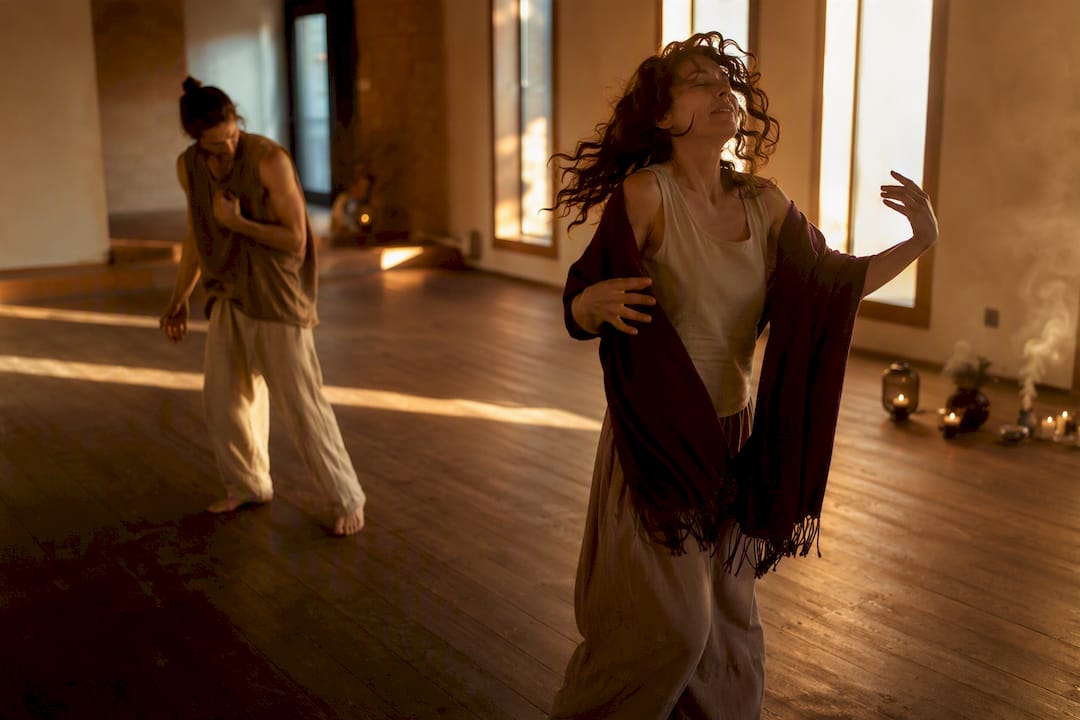 Two dancers moving freely in warm sacred space