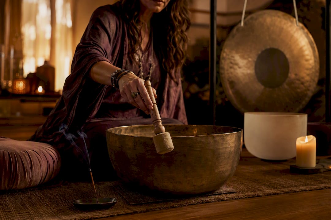 Practitioner playing singing bowl in sacred studio