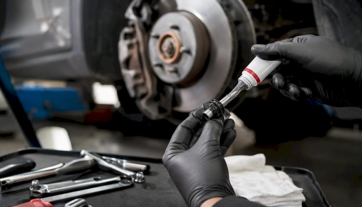 Hands lubricating brake caliper slide pins