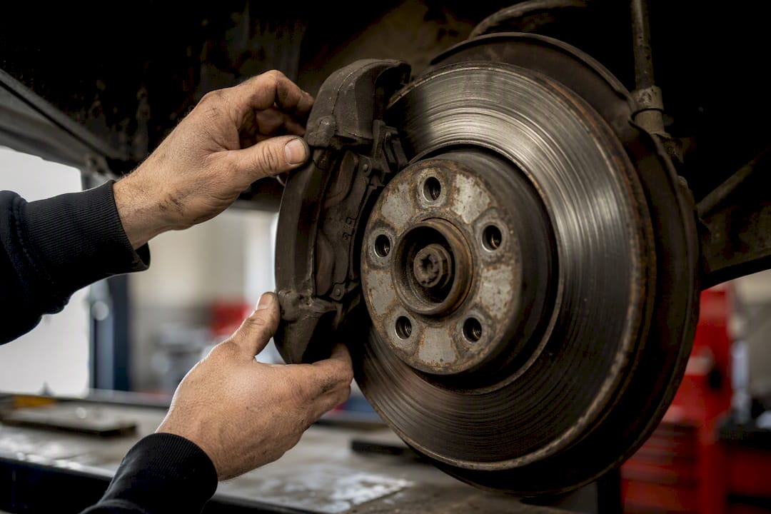 Hands inspecting brake caliper and rotor