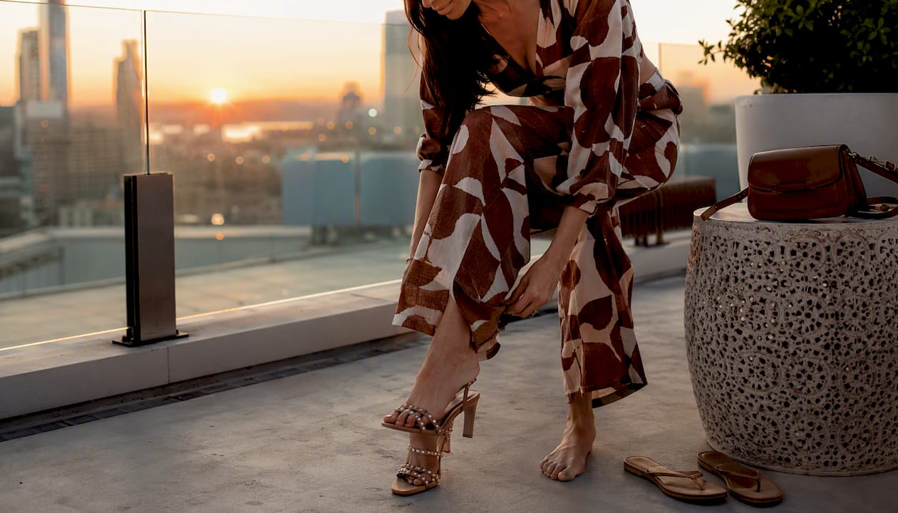 Woman adjusting day-to-night summer outfit on balcony