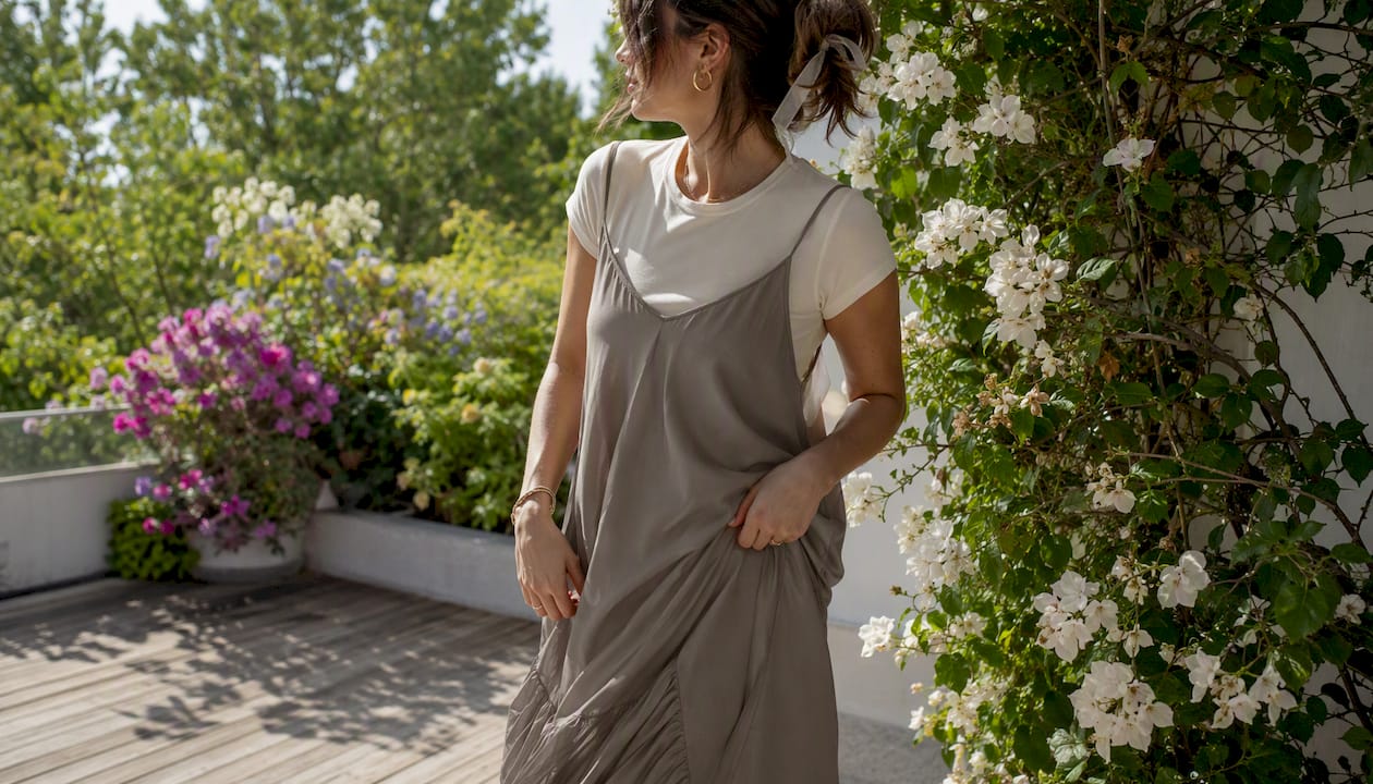 Woman layering slip dress over white tee outdoors