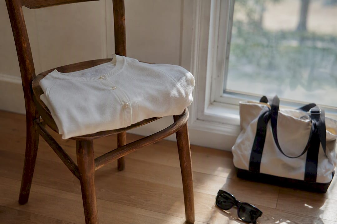Folded cotton cardigan on chair by window