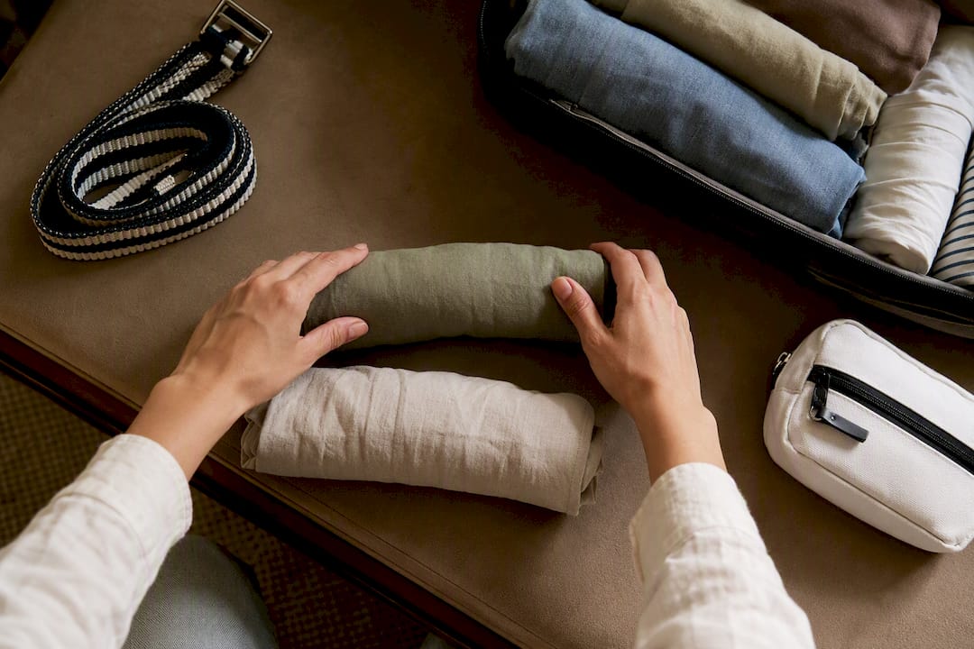 Hands rolling cotton clothes for suitcase