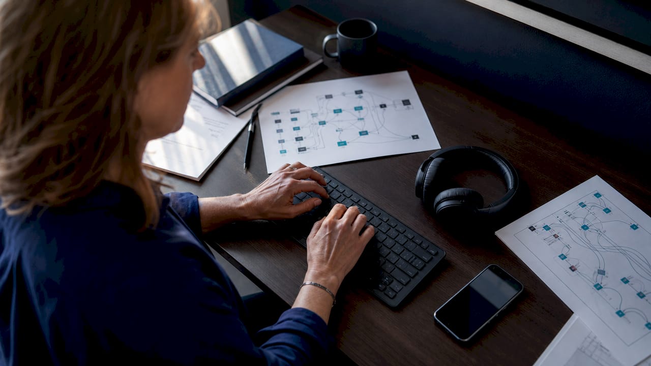 Gros plan sur les mains d'une femme en train de développer une solution middleware dans un environnement de bureau.