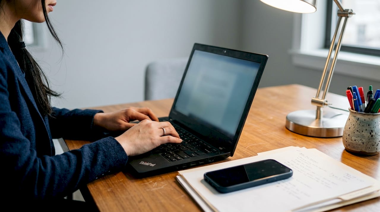 Une femme configure son logiciel CRM sur son ordinateur portable, concentrée sur les paramètres à ajuster.