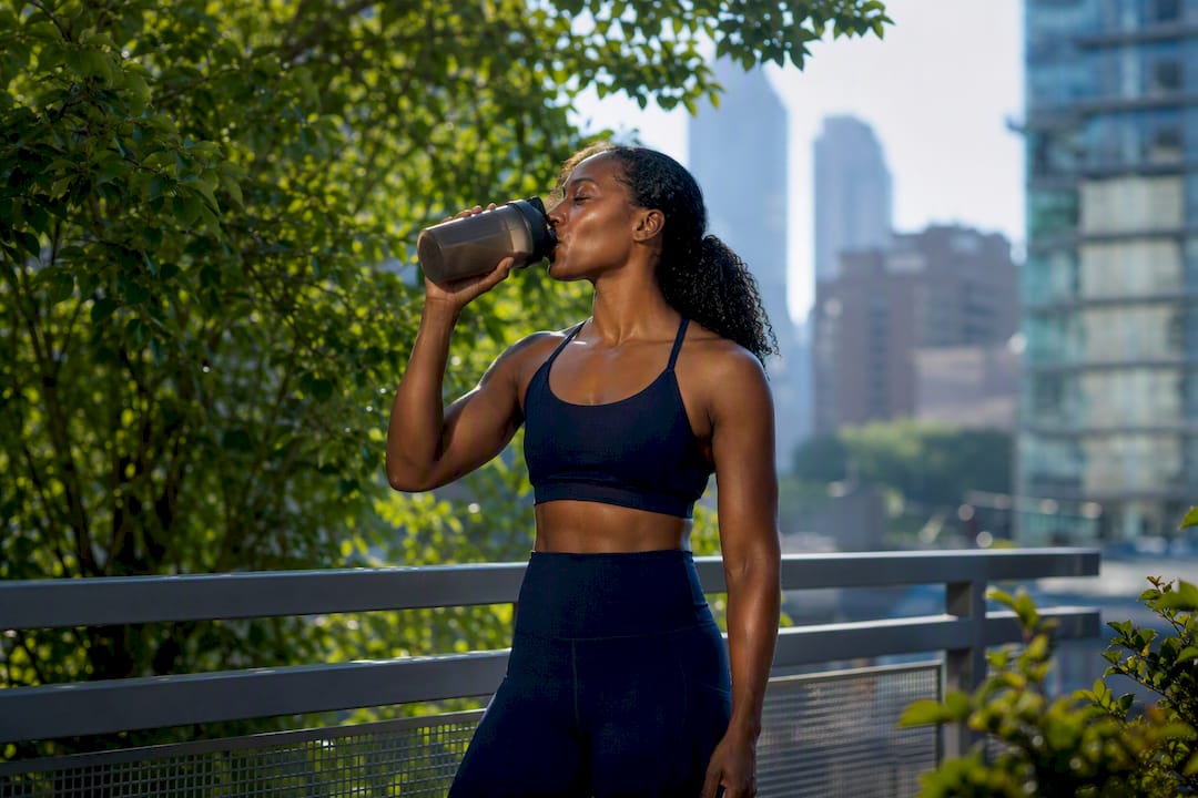 Black woman drinking protein shake outdoors