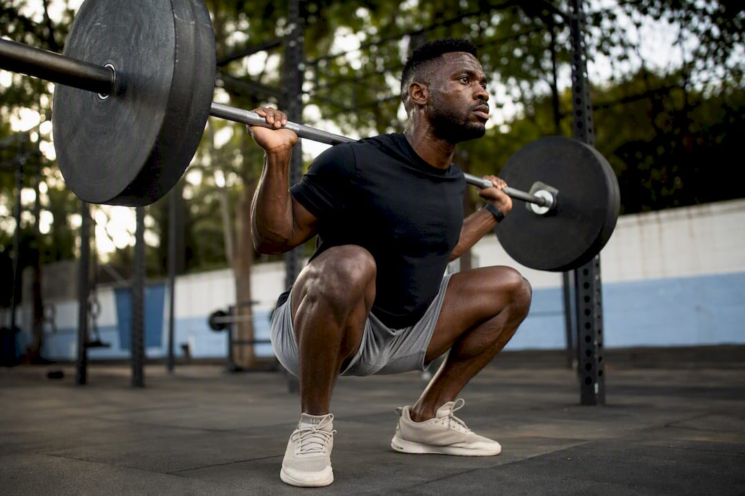 Athlete squatting in gym shorts at gym