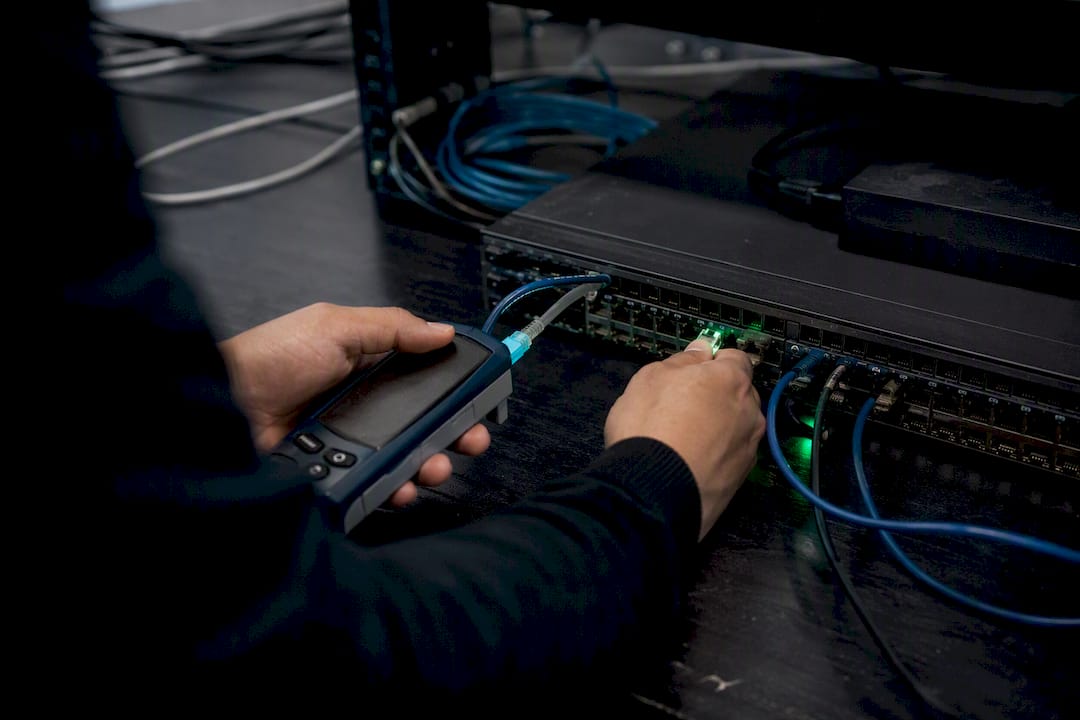 Manos manipulando cables con una herramienta para probar la red